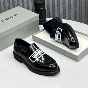 A pair of black leather loafers with white decorative straps, displayed on a white surface with a shoe box and other accessories.