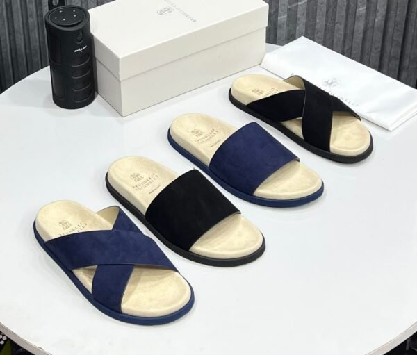 High-quality suede slides in navy and black, displayed with packaging and accessories, showcasing luxury footwear from Jsfootis.