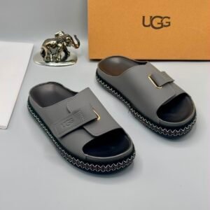 Grey UGG slide sandals with zigzag stitching and gold buckle on a white background, Jsfootis