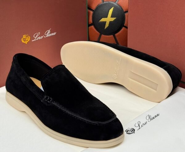 A pair of black suede loafers with cream-colored soles, displayed on a white surface with a brown background, showcasing the Jsfootis brand's commitment to luxury footwear.