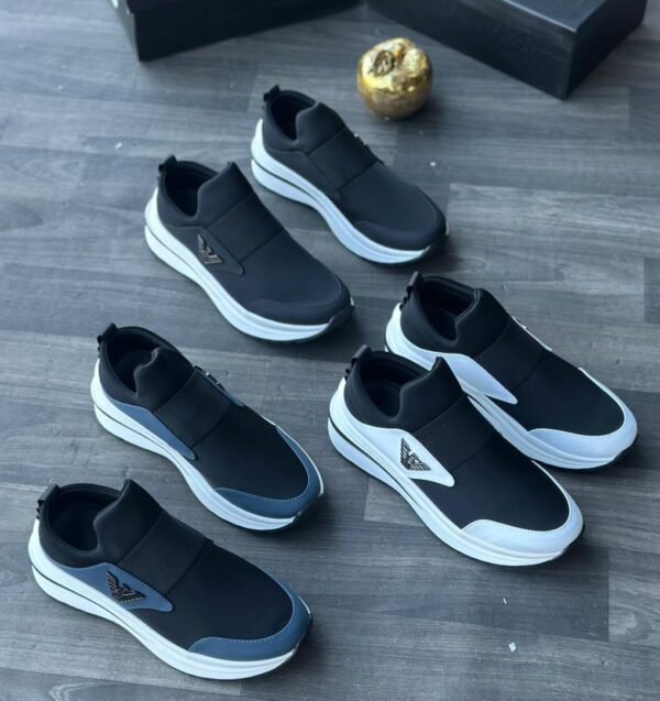 IMG-20260708-WA0059 A collection of black and white sneakers arranged on a wooden floor, showcasing the sleek design and comfort of Jsfootis footwear.