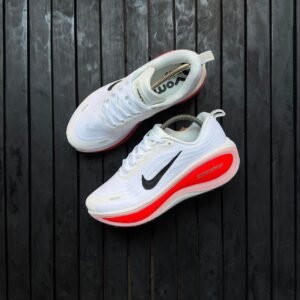 Brand new Nike ZoomX running shoes in white with blue accents and black Nike swoosh logo, displayed with orange Nike shoe box on a dark wooden background | jsfootis