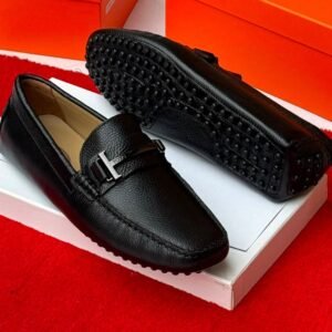 A pair of stylish grey leather loafers with black studs on the sole, displayed on a white shoe box with an orange background, showcasing Jsfootis luxury footwear.