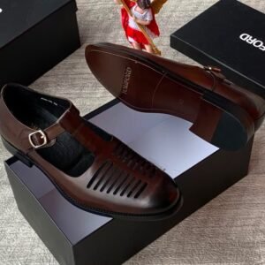 High-quality black leather monk strap shoes with a sleek buckle and ventilation holes, presented on a black shoe box with a reflective surface.