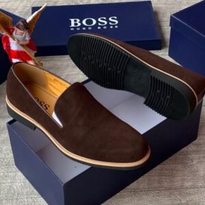 Luxurious black suede loafers with tan soles, presented on a navy blue shoe box with the 'BOSS' logo, embodying JC Luxury Footwears' high-end style.