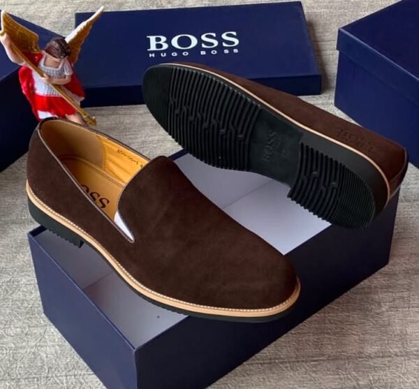 Luxurious black suede loafers with tan soles, presented on a navy blue shoe box with the 'BOSS' logo, embodying JC Luxury Footwears' high-end style.