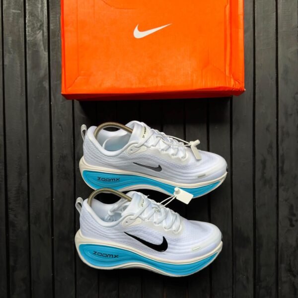 root Brand new Nike ZoomX running shoes in white with blue accents and black Nike swoosh logo, displayed with orange Nike shoe box on a dark wooden background | jsfootis
