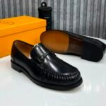 A pair of black leather loafers displayed with their box, showcasing the shoe's sleek design and luxurious leather finish.