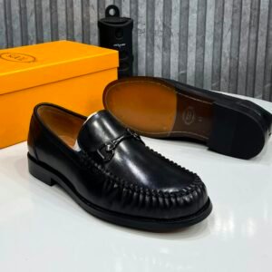 A pair of black leather loafers displayed with their box, showcasing the shoe's sleek design and luxurious leather finish.