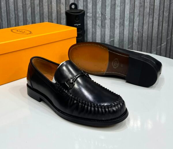 root A pair of black leather loafers displayed with their box, showcasing the shoe's sleek design and luxurious leather finish.