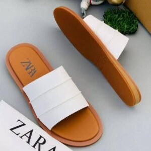 A pair of white slides with brown soles and a ZARA box, perfect for comfortable and stylish footwear.