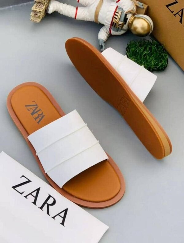 A pair of white slides with brown soles and a ZARA box, perfect for comfortable and stylish footwear.